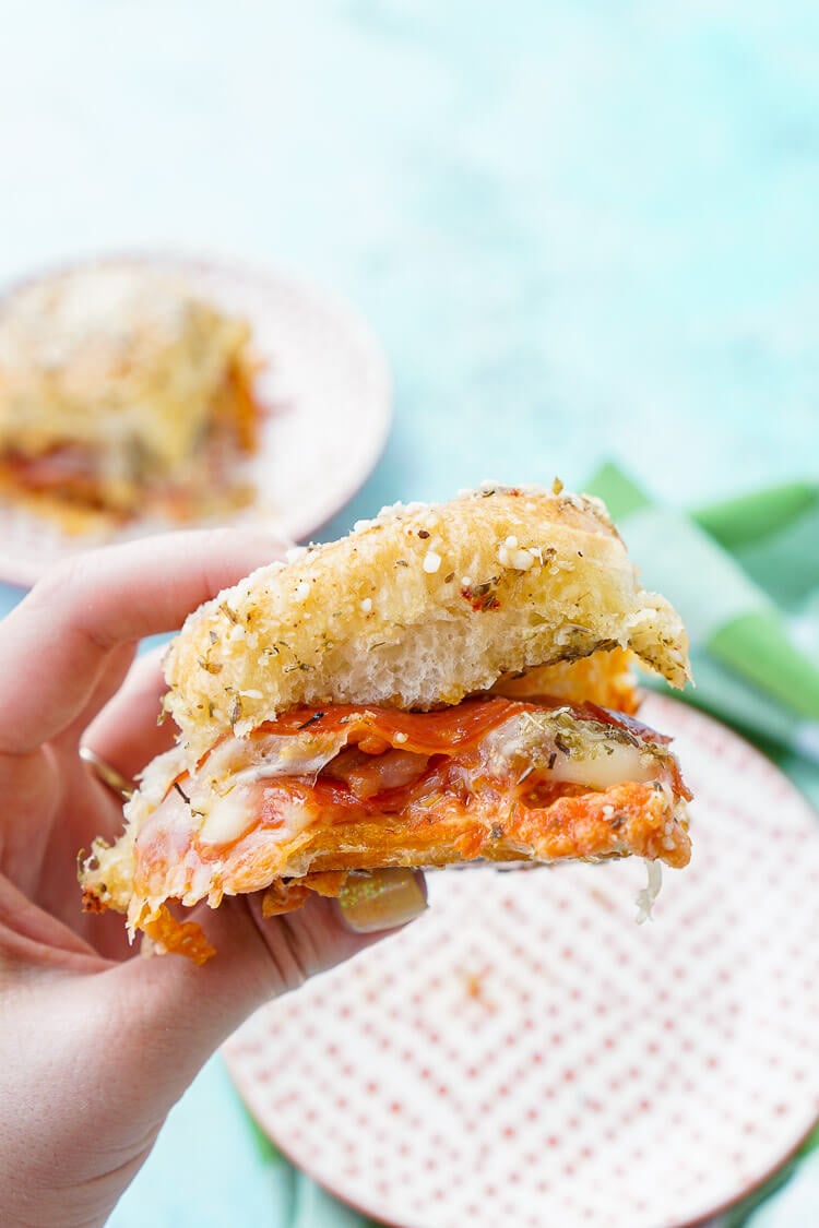 These Easy Pizza Sliders are so simple to make and are sure to be a family favorite! Layers of sauce, mozzarella, bacon, and pepperoni are baked in soft dinner rolls coated in butter, herbs, and parmesan!