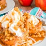 Apple french toast on a white plate topped with caramel and whipped cream.