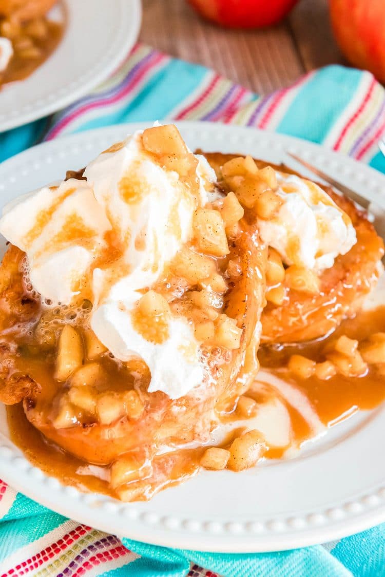 French toast stuffed and topped with apples and whipped cream on a white plate.