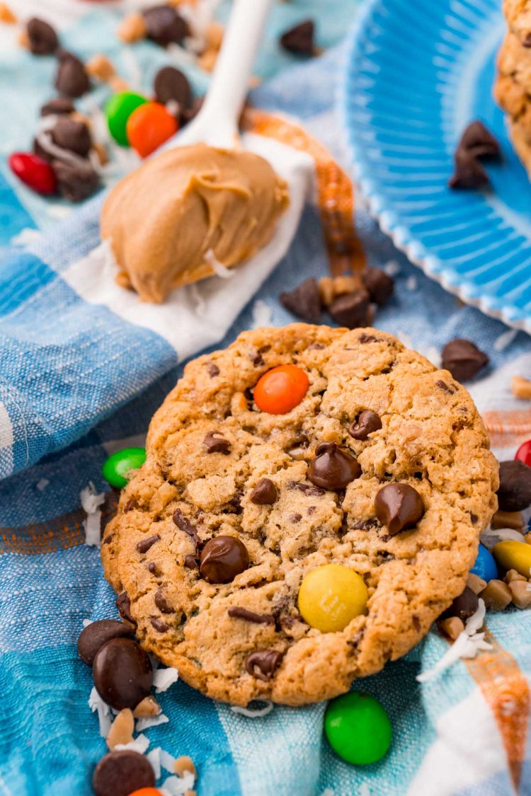 Monster Cookies on a blue napkin with M&Ms and chocolate chips scattered around.