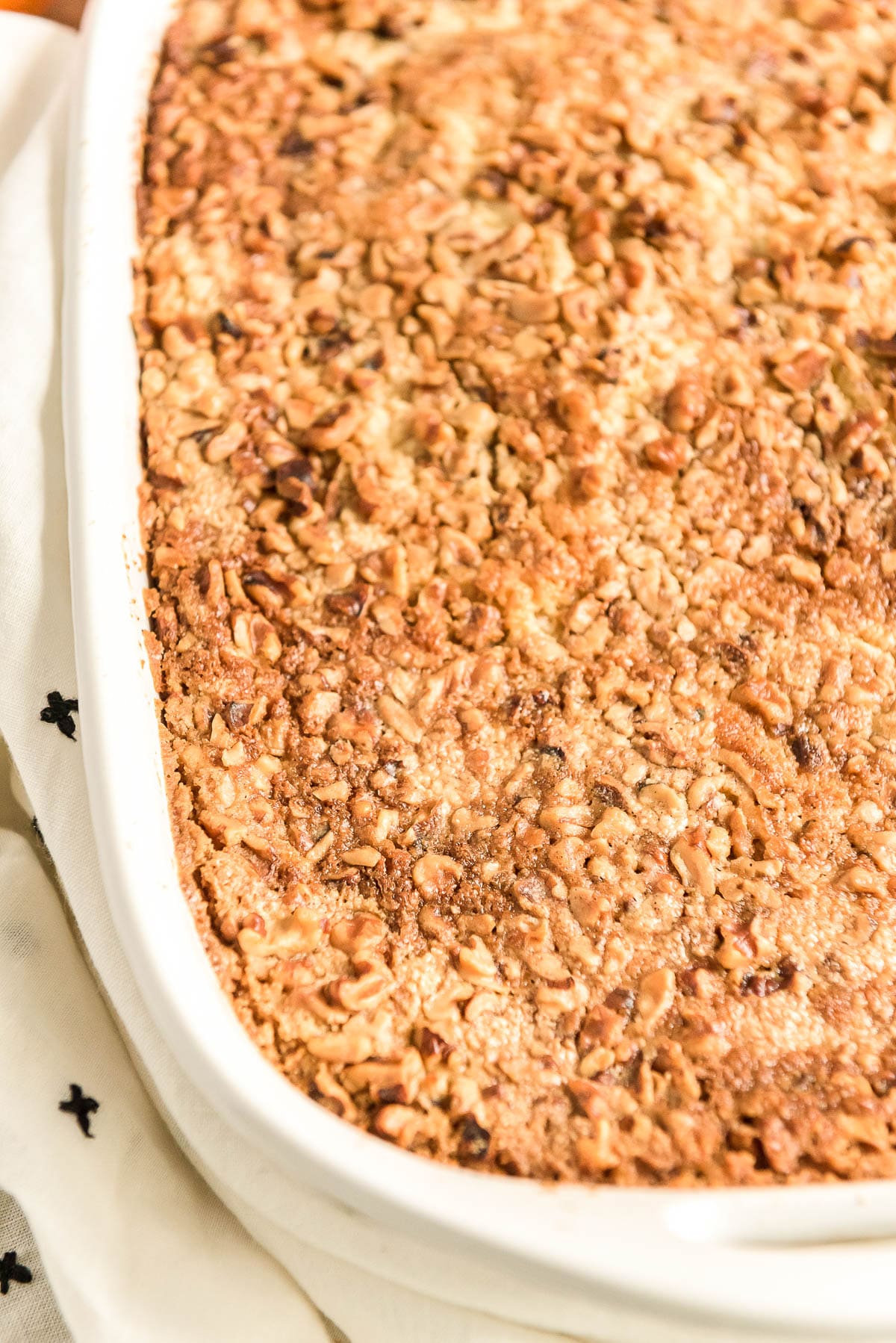 Close up photo of pumpkin cake topped with nuts still in the baking dish.