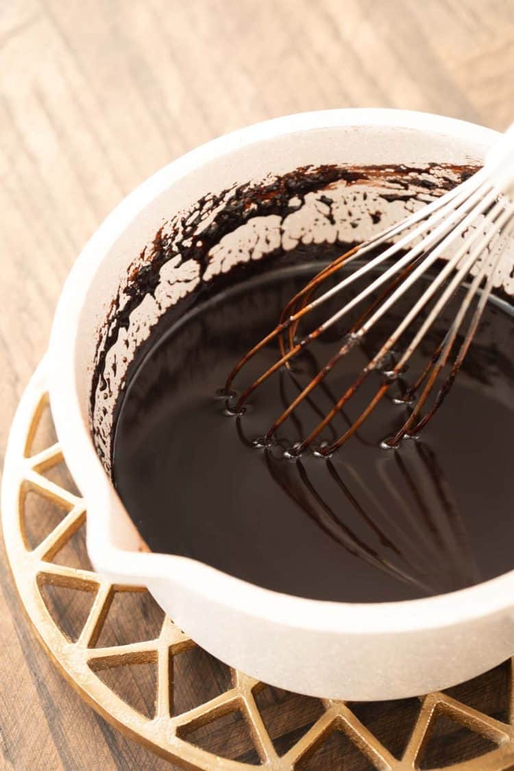 Chocolate syrup in a saucepan with a whisk.