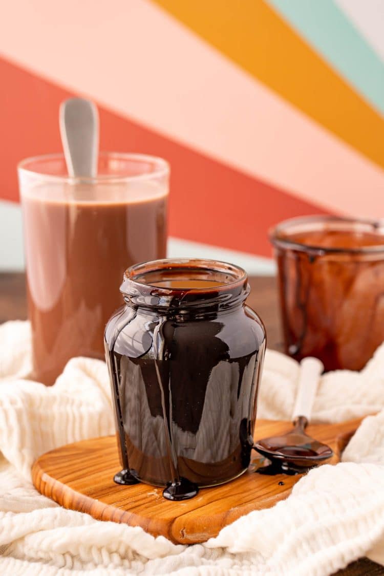 A jar of Chocolate Syrup on a wooden cutting board.