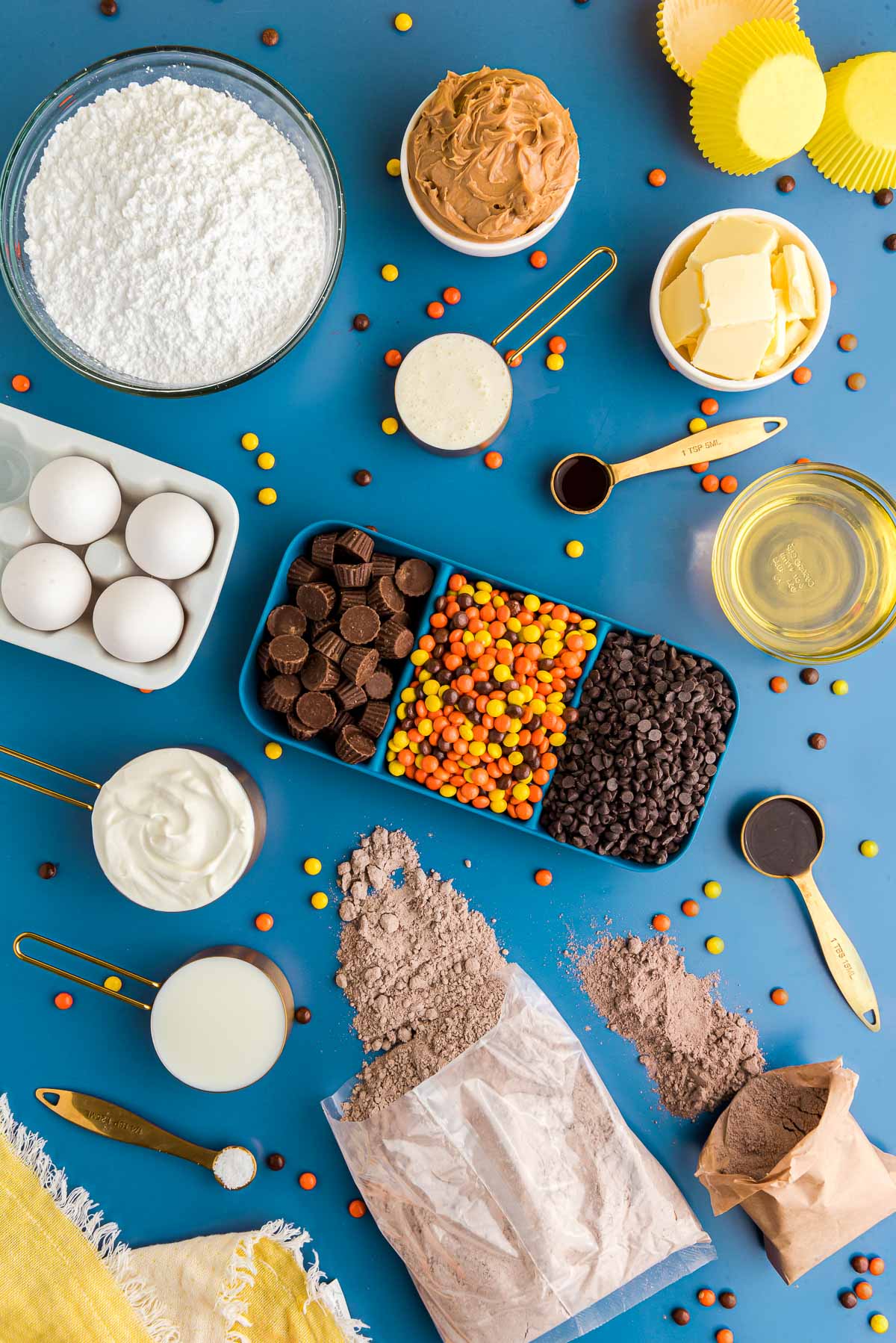 Overhead photo of ingredients prepped to make peanut butter chocolate cupcakes on a blue surface.