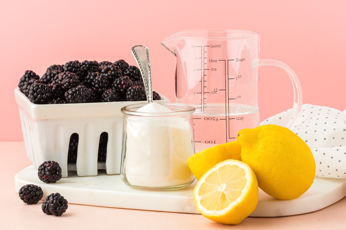 Ingredients to make blackberry simple syrup on a white serving tray.