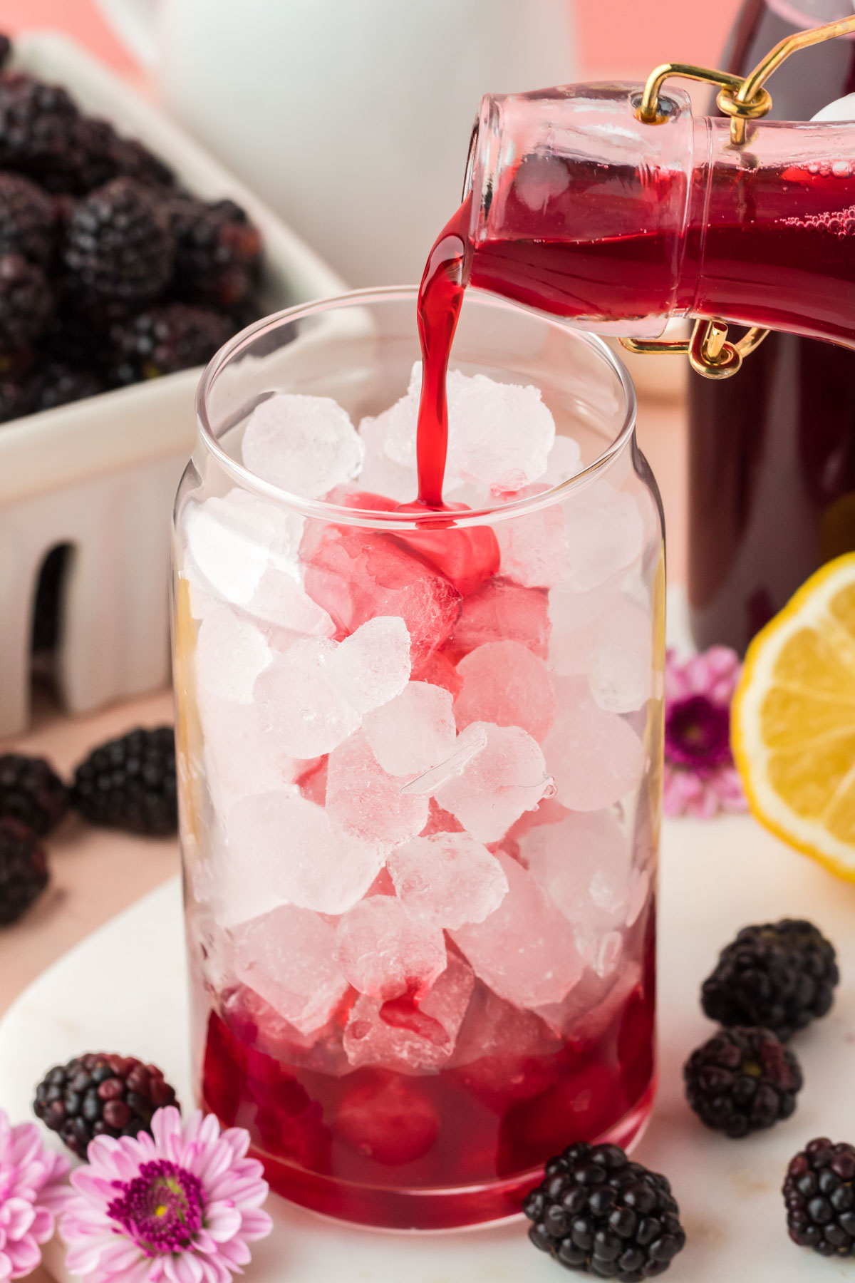 Blackberry simple syrup being poured into a glass with ice.