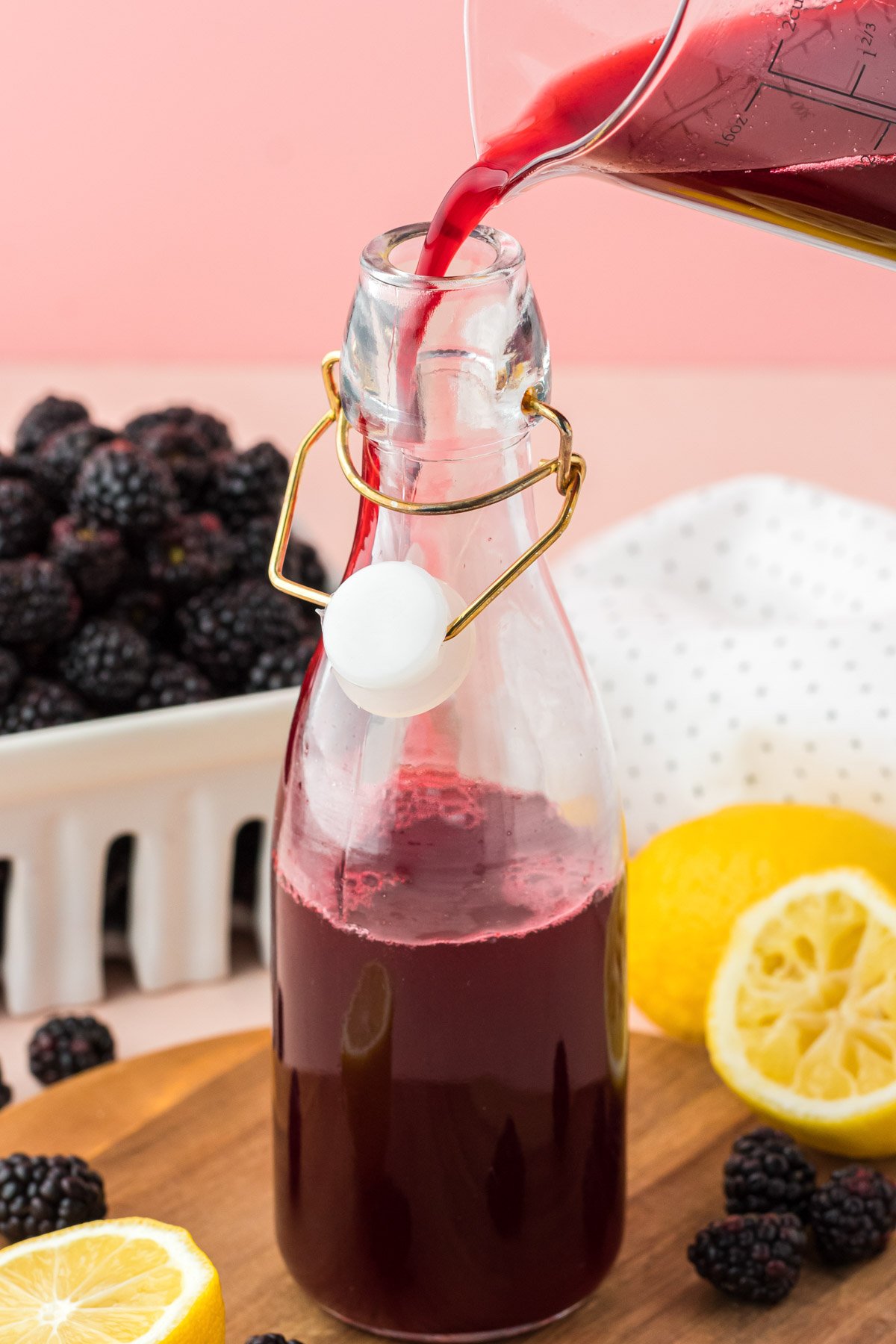 Blackberry simple syrup being poured into a bottle for storing.