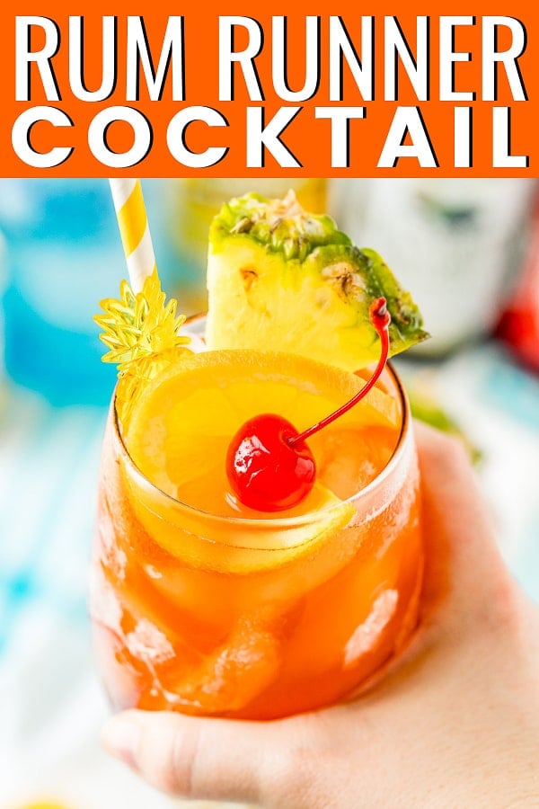  Hand Holding a Rum Runner Cocktail garnished with orange, pineapple, and orange.  