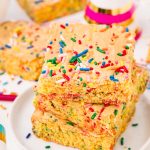 Close up photo of cake mix brownies on a white plate on a white table surrounded by sprinkles and birthday hats.