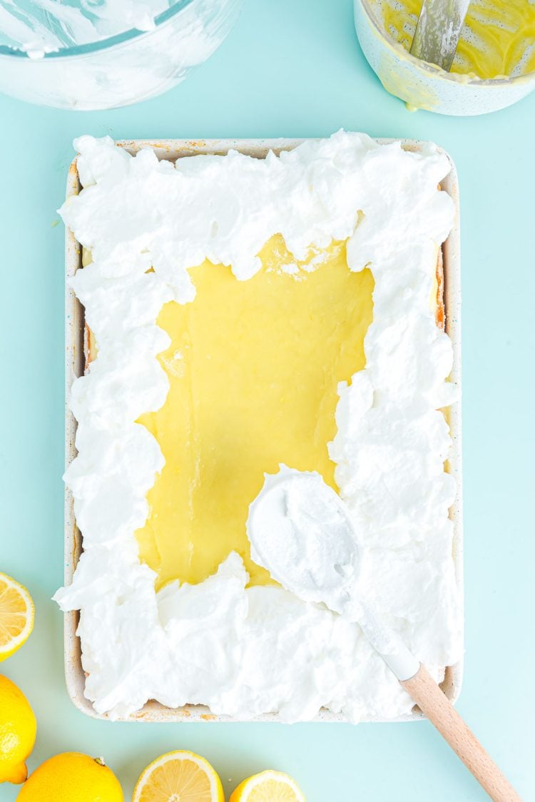 Overhead photo of a lemon meringue slab pie being covered with meringue. 
