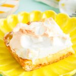 Close up photo of a slice of lemon meringue slab pie on a yellow plate on a blue surface.