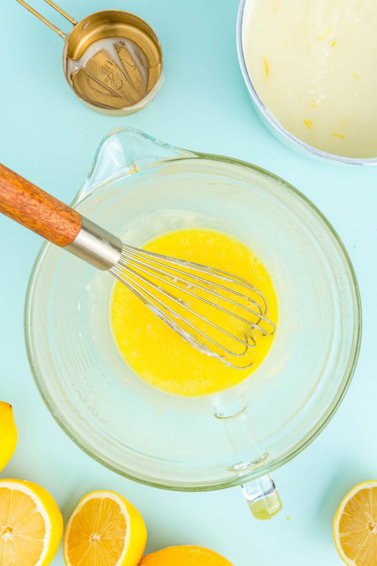 Egg yolks beaten in a large glass mixing bowl.