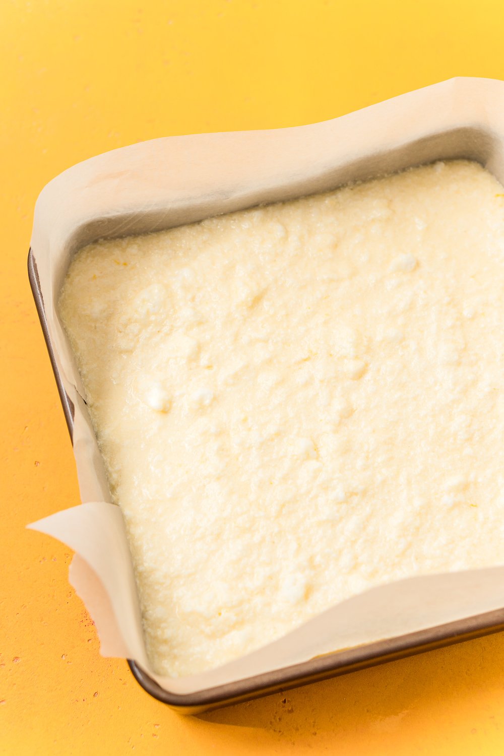 Lemon Magic Cake batter poured into a prepared 8x8-inch baking pan.