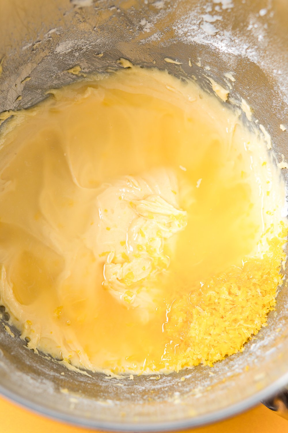 Lemon juice and zest added to lemon cake batter in a metal mixing bowl.