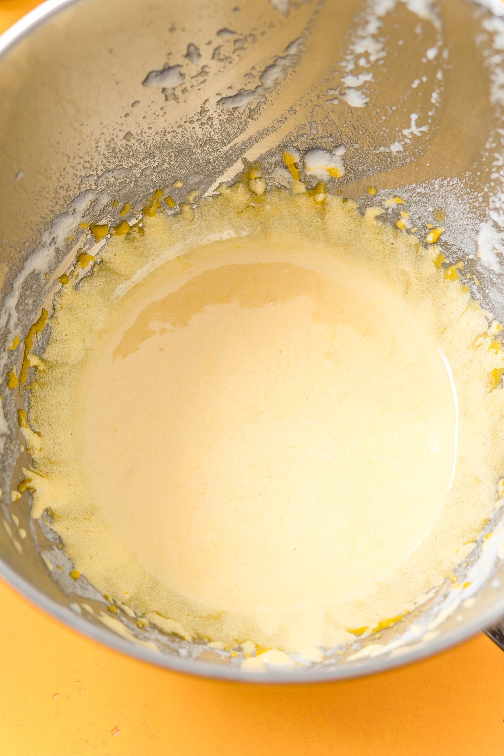 Egg yolks and sugar beaten together in a metal mixing bowl.