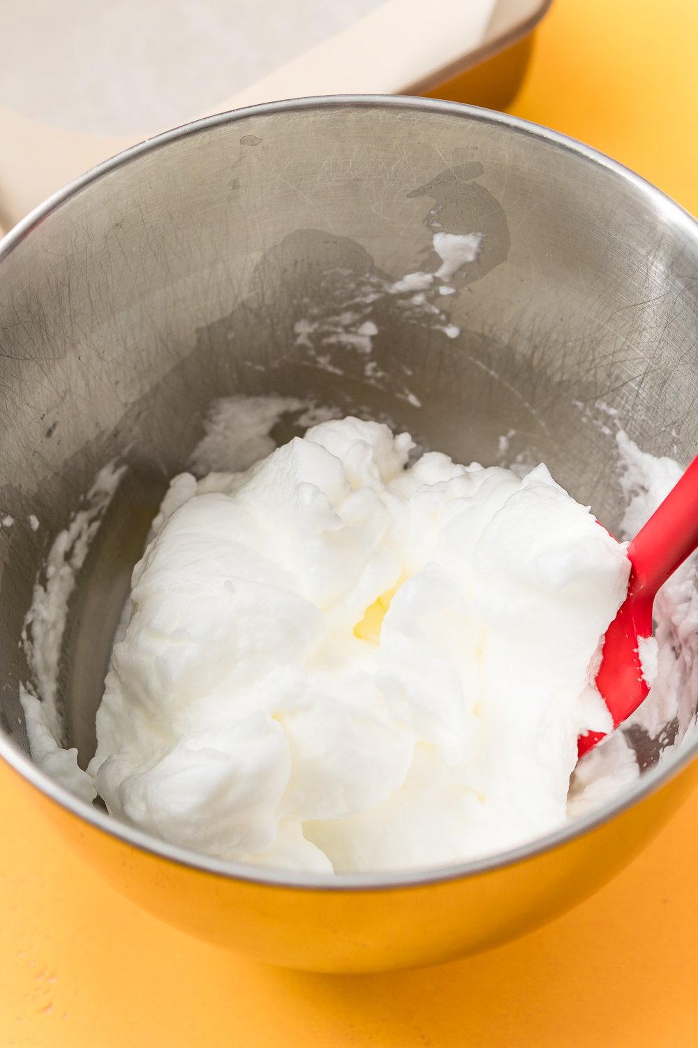 Egg whites that have been beaten stiff in a metal mixing bowl.