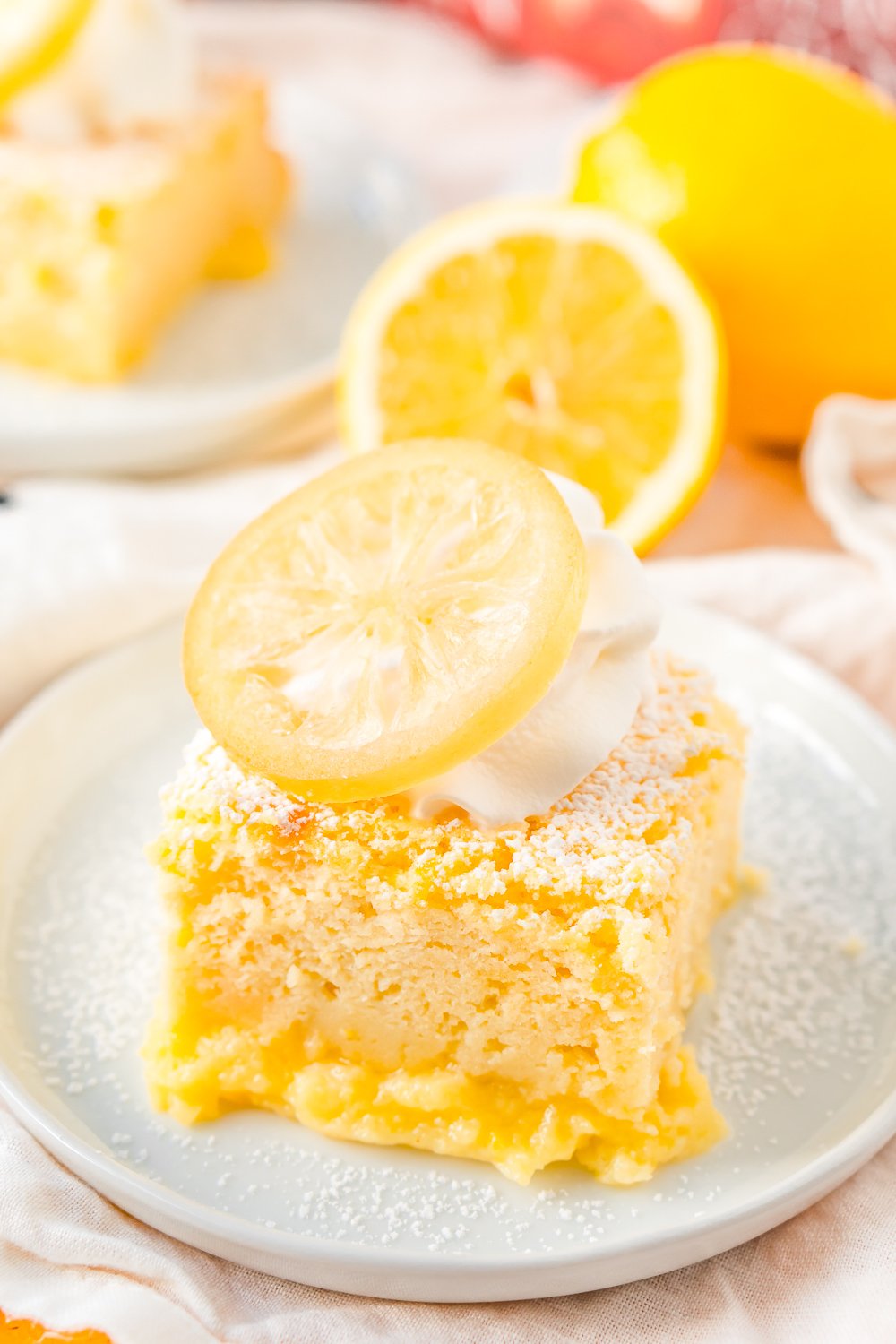 Lemon Cake on small white plate with lemon in the background.