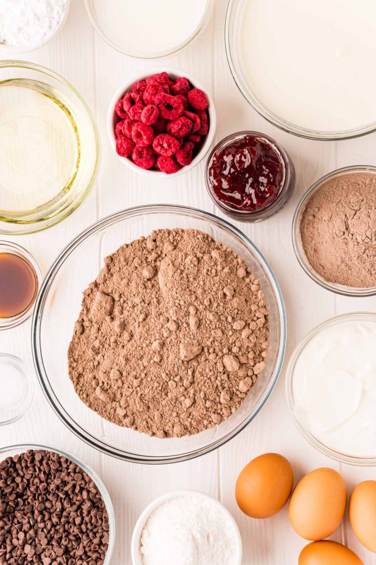 Ingredients to make chocolate raspberry cupcakes on a white table.