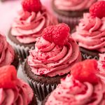 Close up photo of a chocolate cupcakes topped with raspberry frosting.