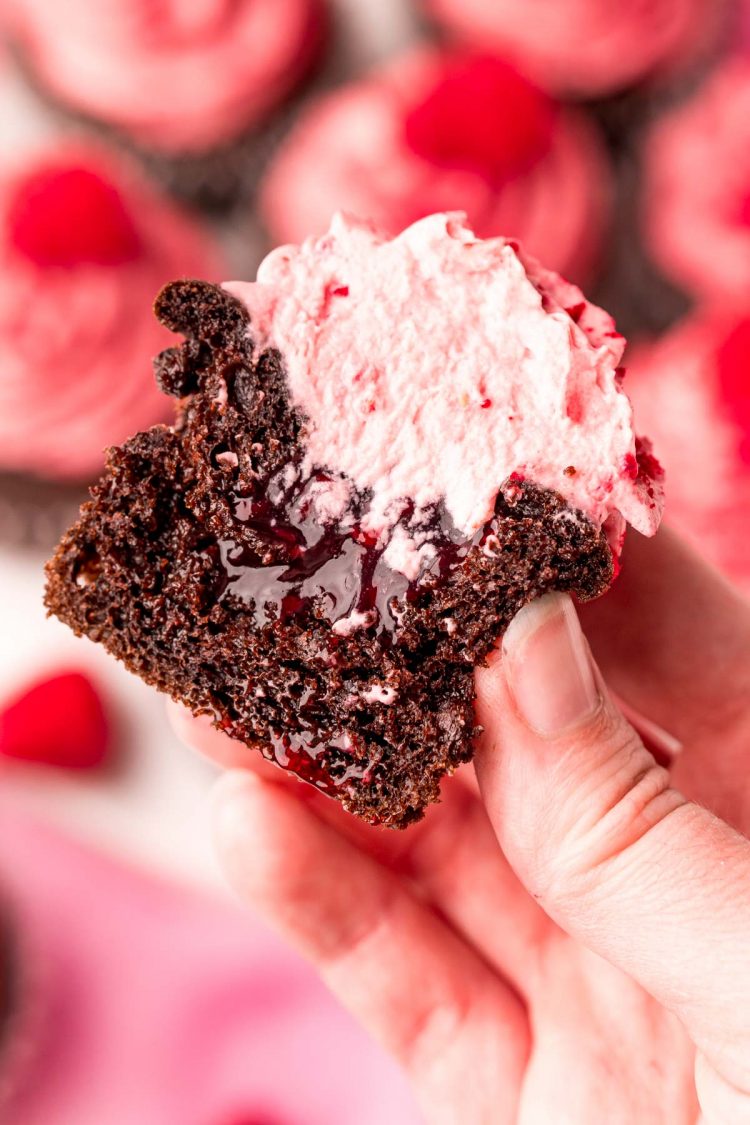 A chocolate raspberry cupcake that's been sliced in half to show the filling.