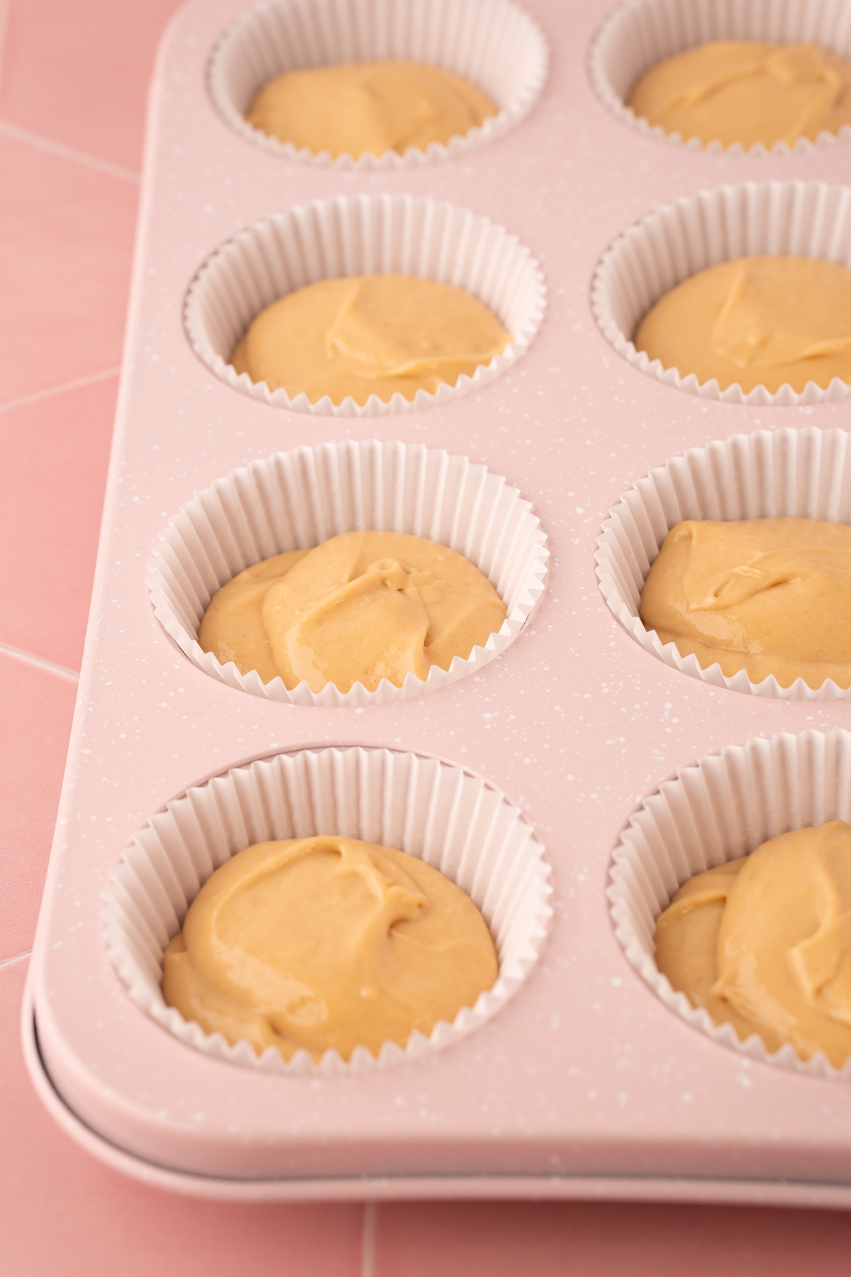 Cupcake batter in liners in a pan ready to bake.