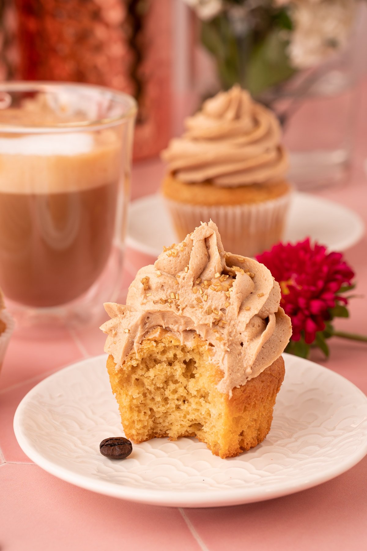 A French Vanilla Cupcake on a white plate with a bite missing.