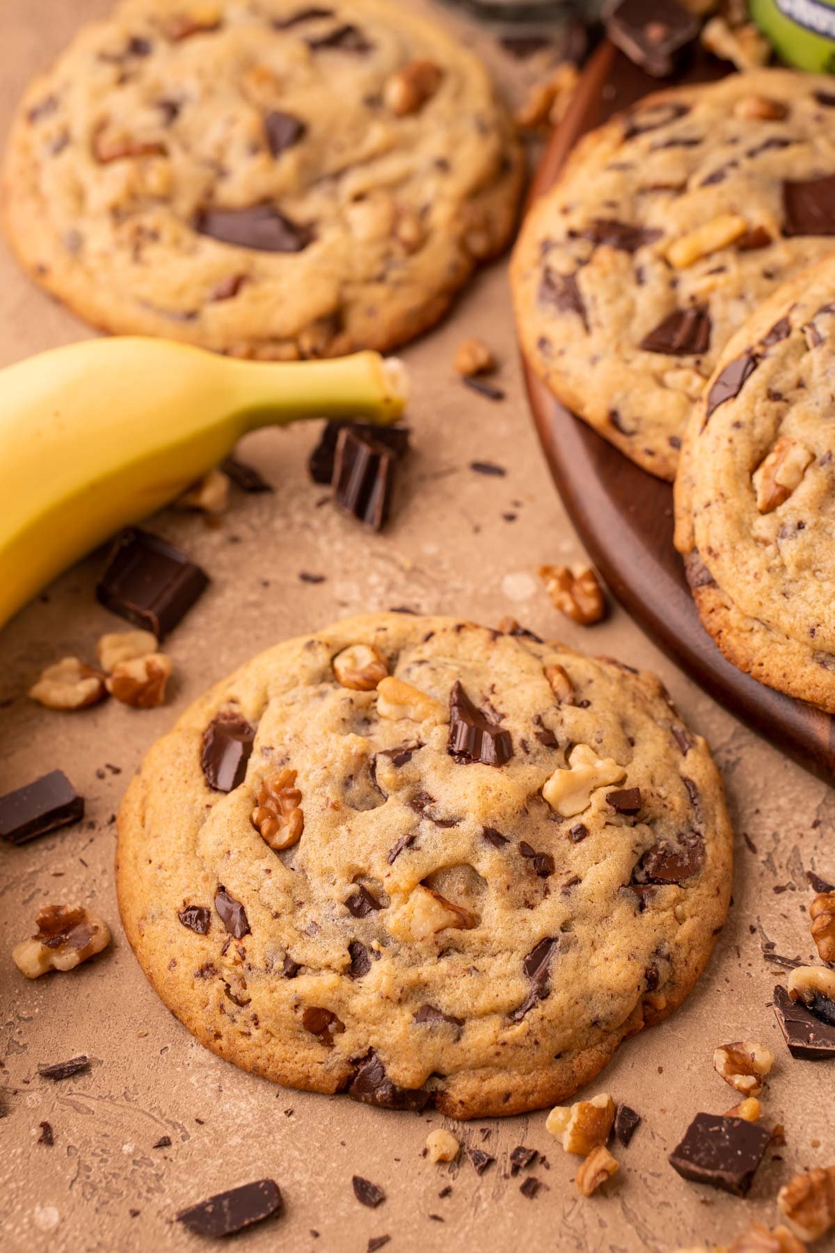 Chunky Monkey Cookies on a table with chocolate, walnuts, and banana around it.
