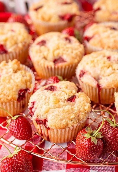 Strawberry muffins on a copper wire rack on a gingham napkin.