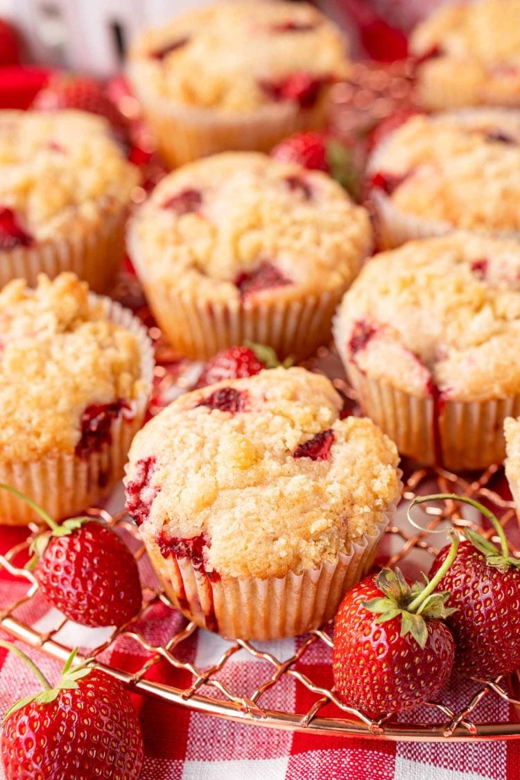 Strawberry muffins on a copper wire rack on a gingham napkin.