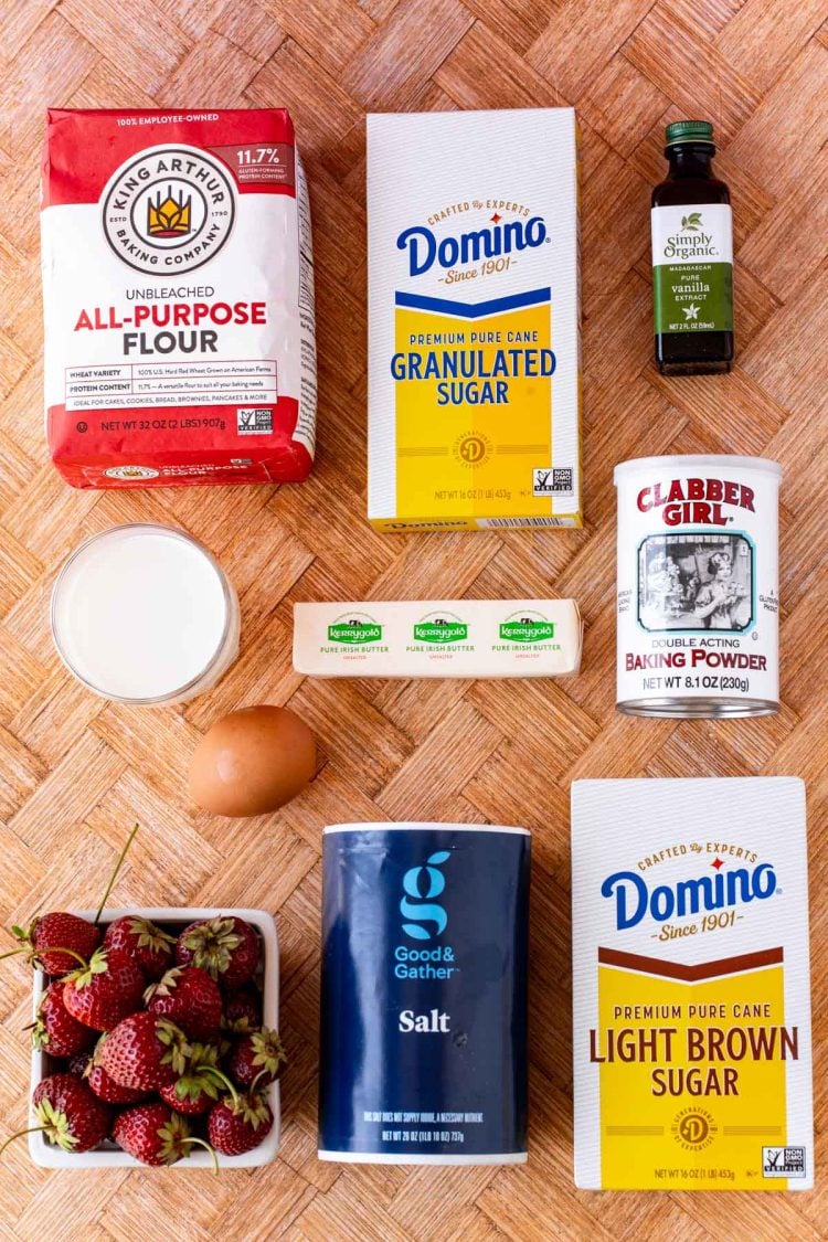 Ingredients to make strawberry muffins on a wooden table.