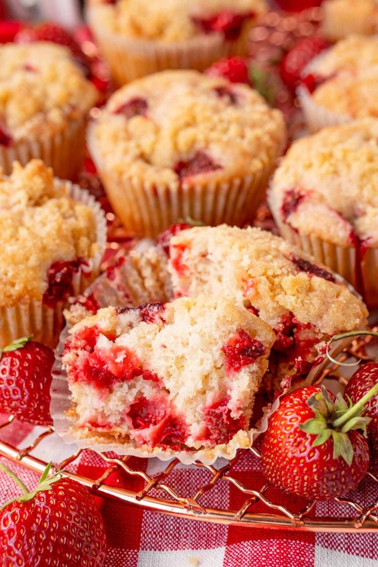 Strawberry muffins on a cooling rack, the front one has been broken in half.