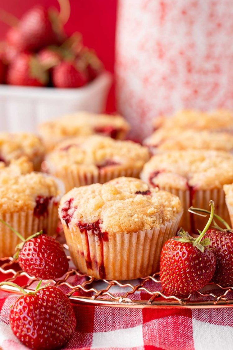 Strawberry muffins on a copper wire rack on a gingham napkin.