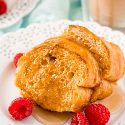 Slices of Caramel Macchiato French Toast on a white plate with raspberries.