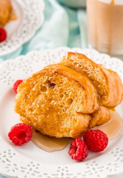 Slices of Caramel Macchiato French Toast on a white plate with raspberries.