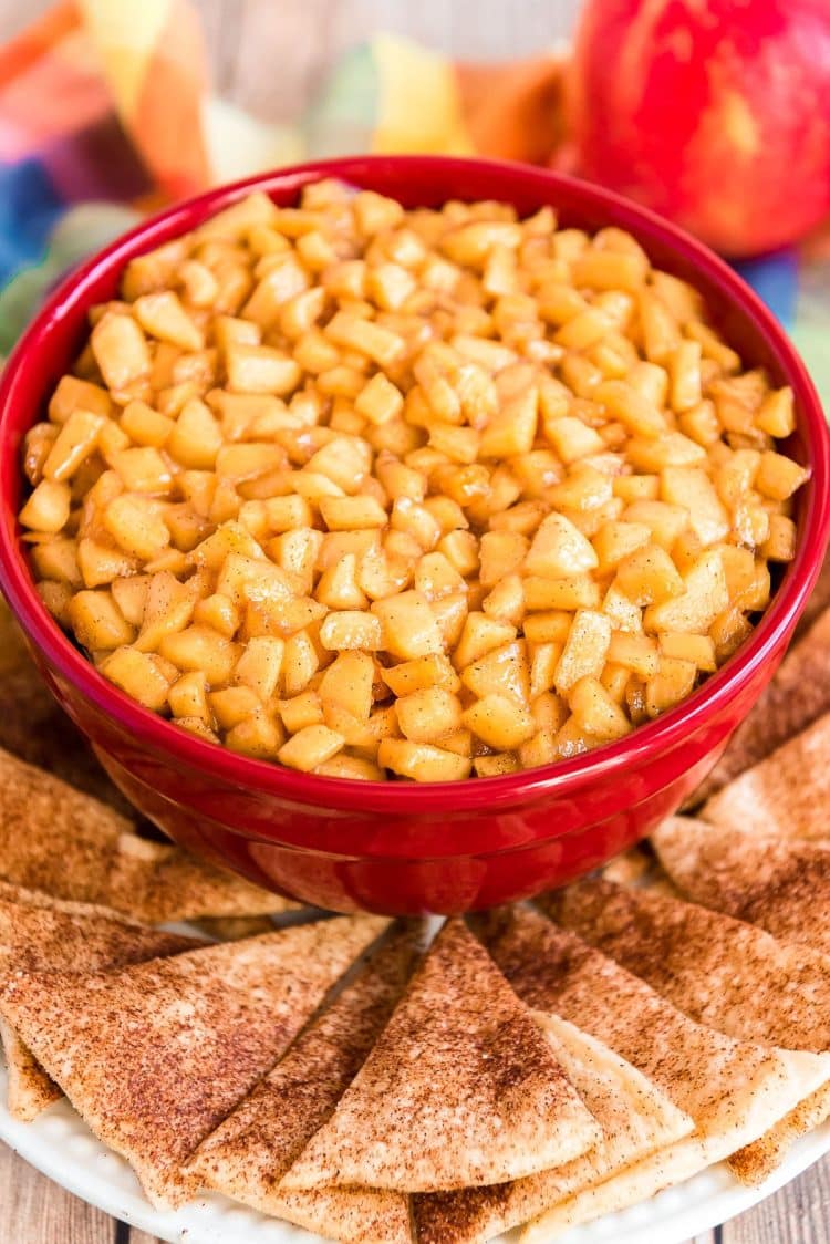 Caramel Apple Dip in a red bowl on a plate with pie crust chips.