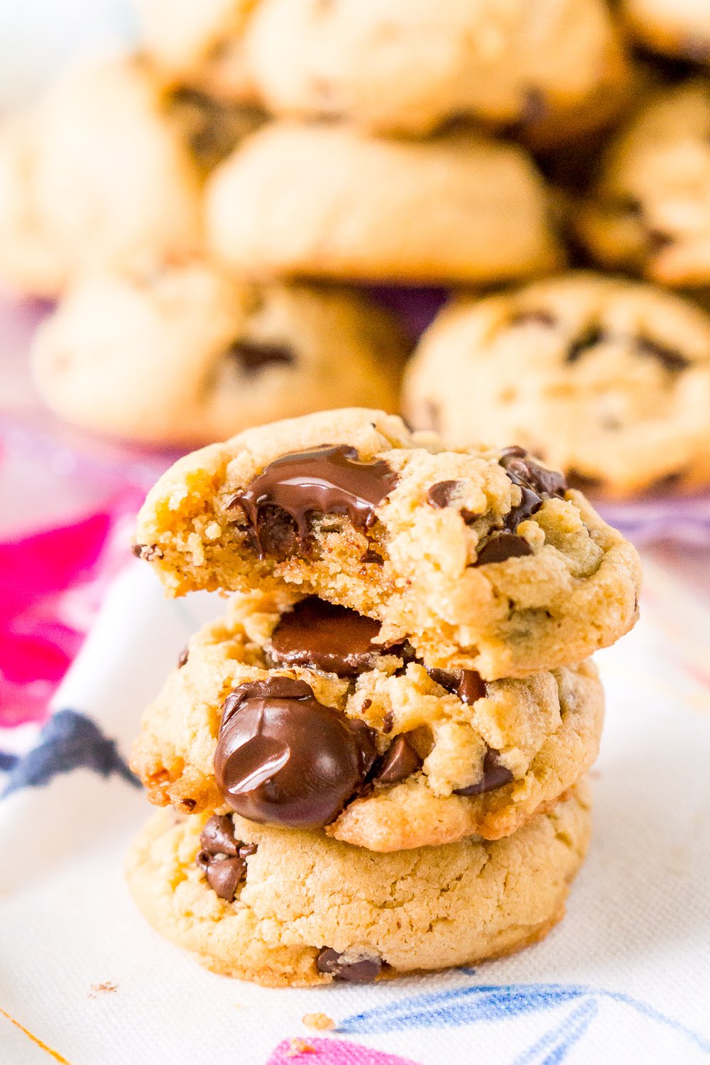 Peanut Butter Chocolate Chip Cookies stacked on top of each other. The top cookie has a bite taken out of it.