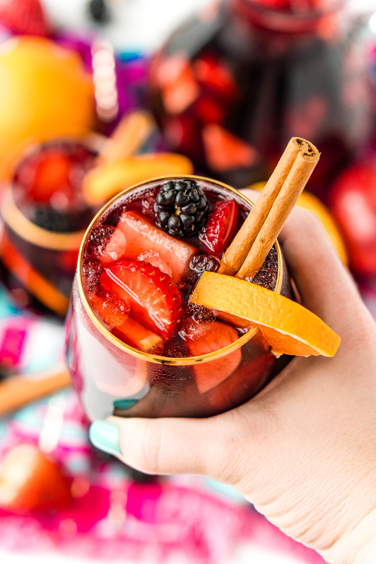 Woman's hand holding a glass filled with sangria wine.