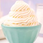 Close up photo of a light blue bowl that has whipped cream piped into it.