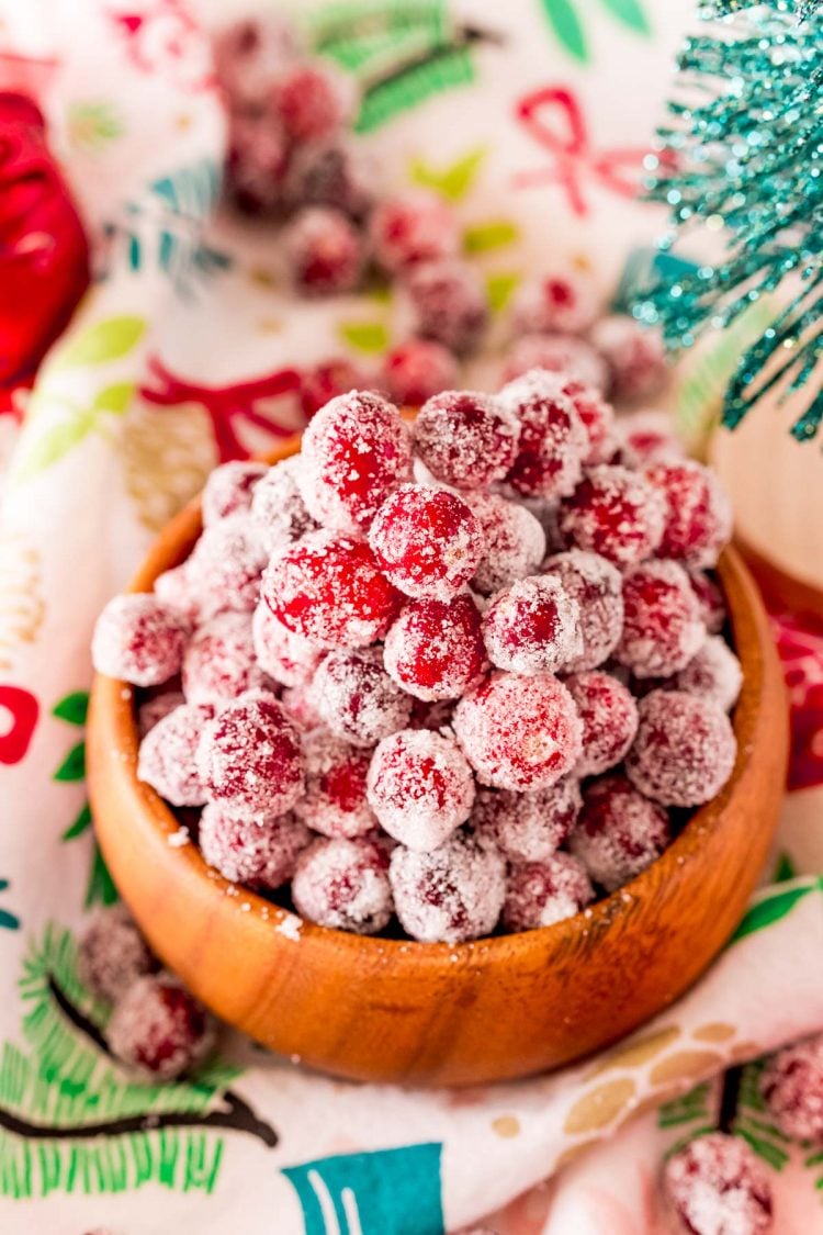 Close up photo of sugared cranberries in a wooden bowl.
