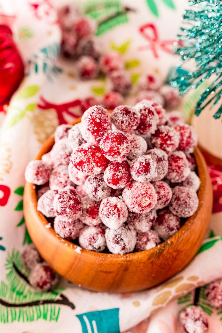 Close up photo of sugared cranberries in a wooden bowl.