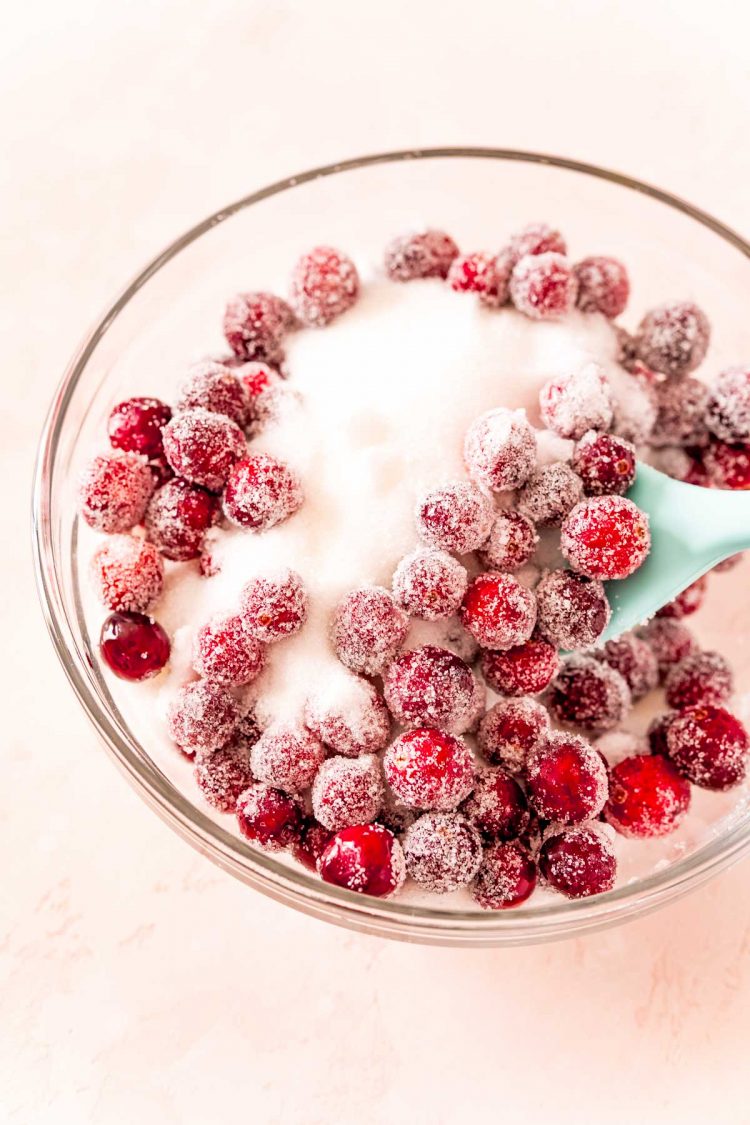 Cranberries being tossed in a bowl of sugar.