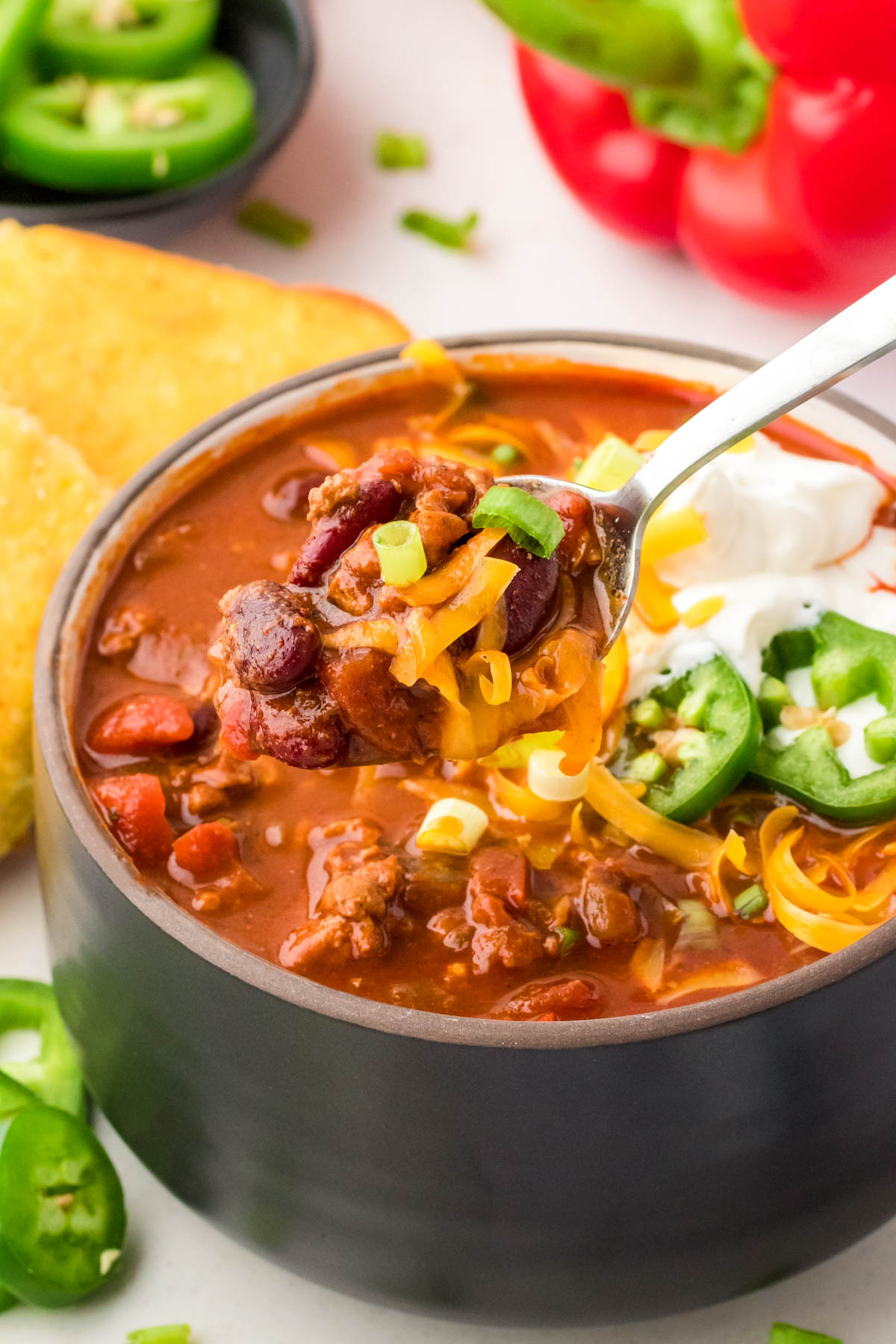 A spoonful of turkey chili coming out of a bowl.