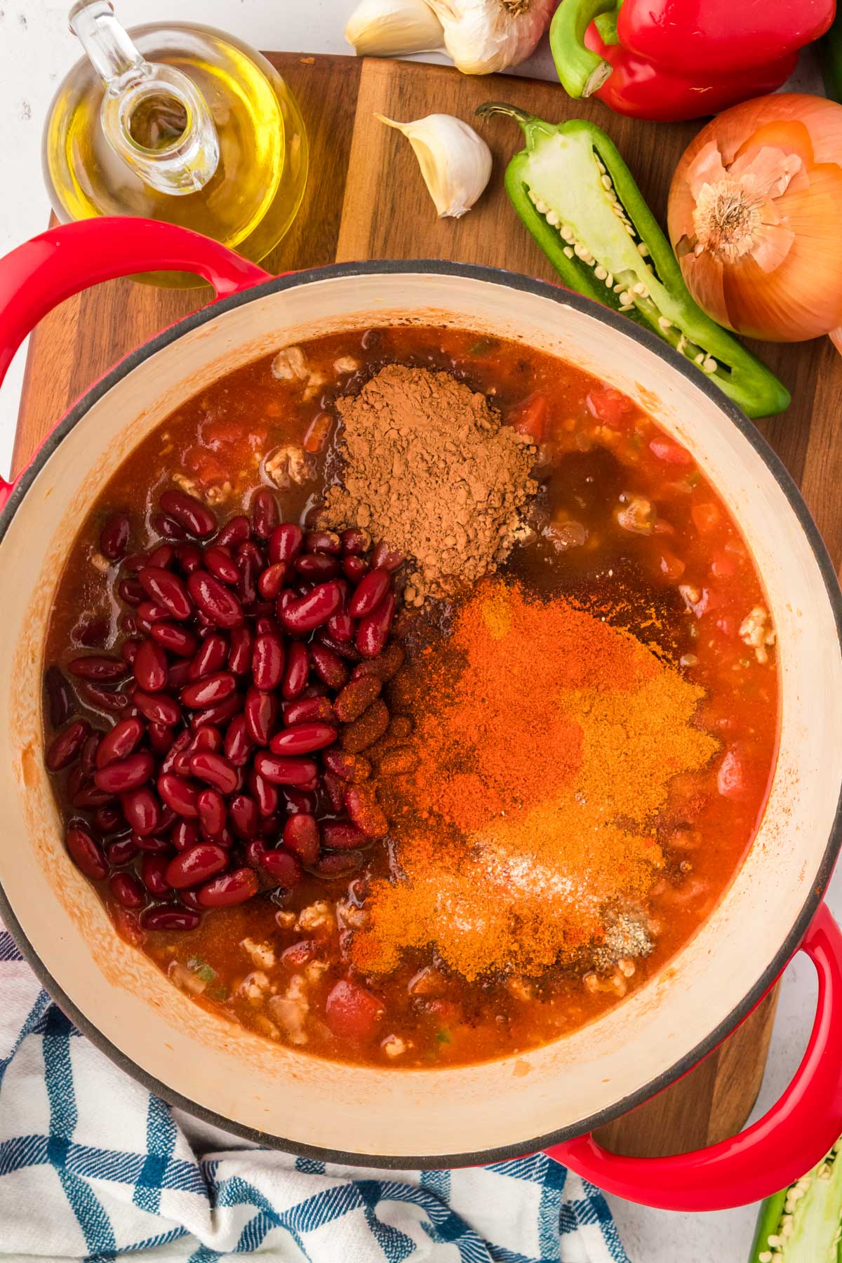 Kidney beans and spiced being added to a Dutch oven to make chili.