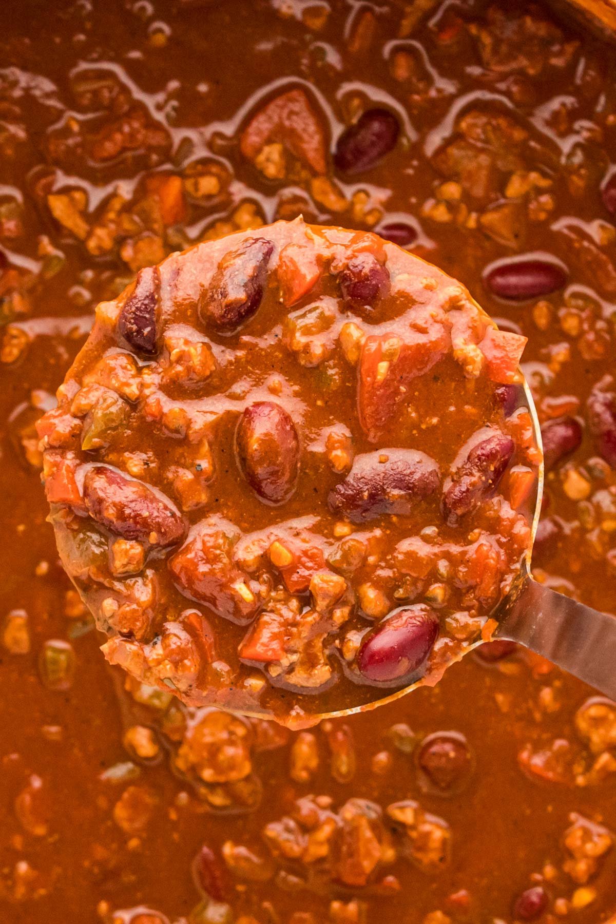 A ladle scooping turkey chili out of a pot.