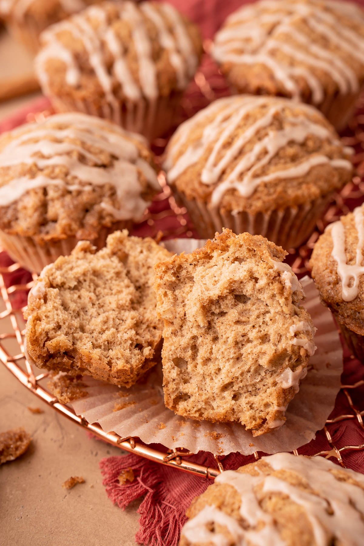 A vanilla chai muffins split open on a copper wire rack with other muffins.