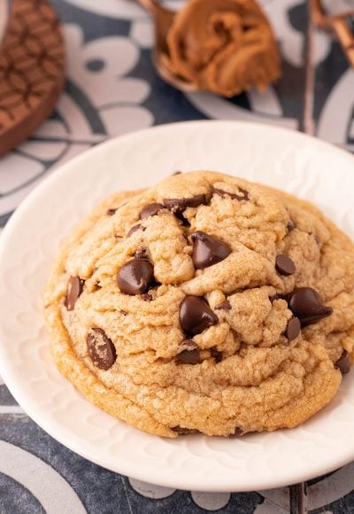 Close up oh a big cookie butter chocolate chip cookie on a white plate.