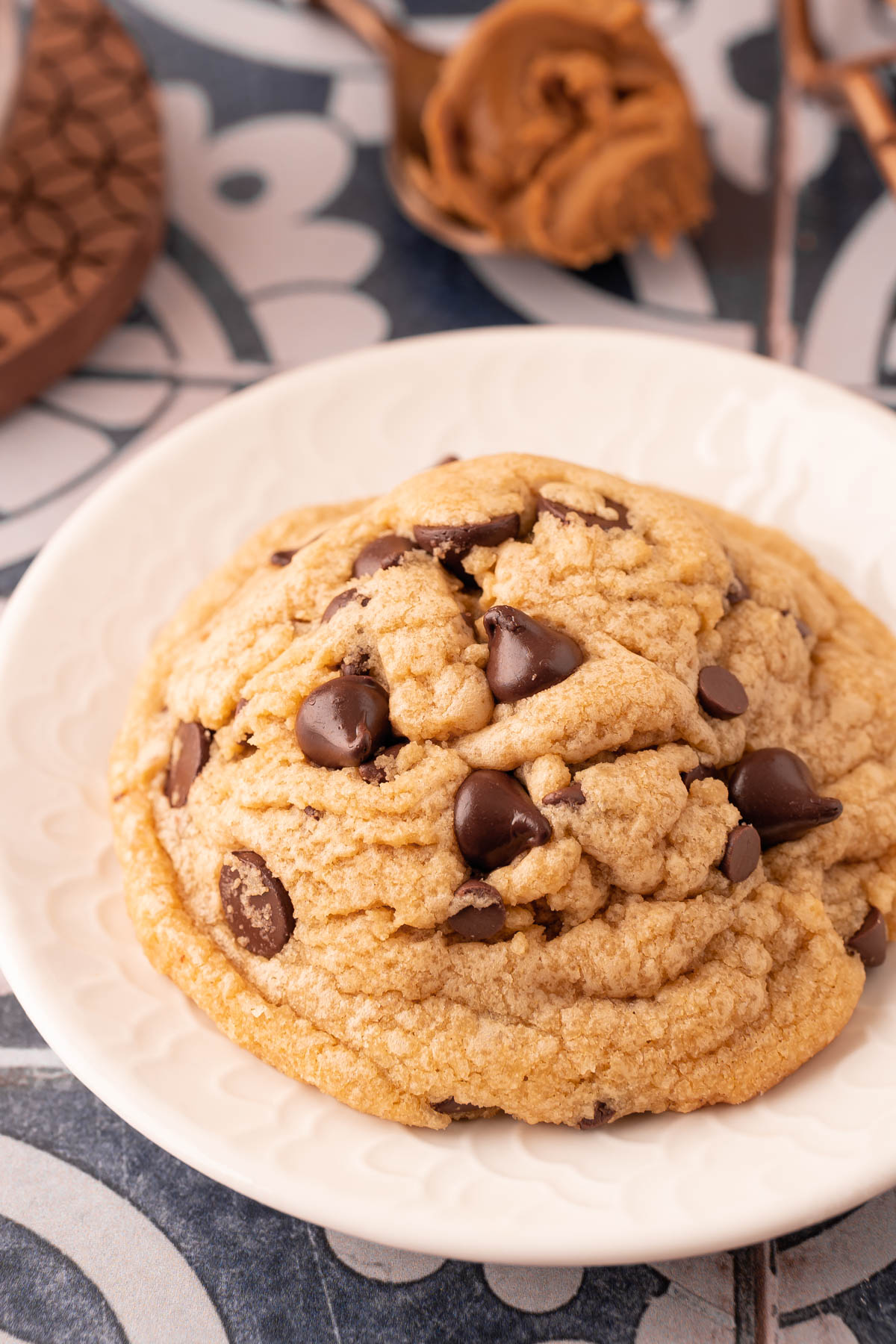 Close up oh a big cookie butter chocolate chip cookie on a white plate.