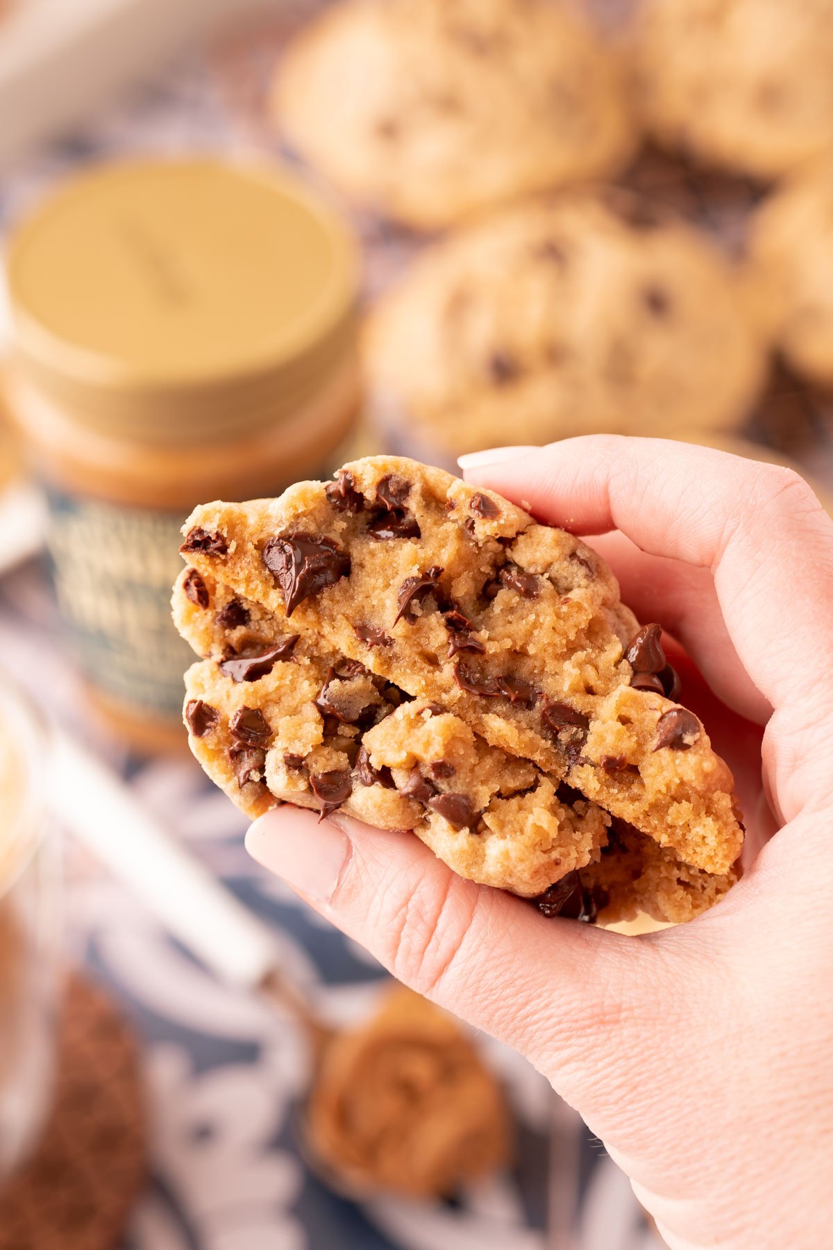 A woman's hand holding a cookie butter chocolate chip cookie that's been broken in half.