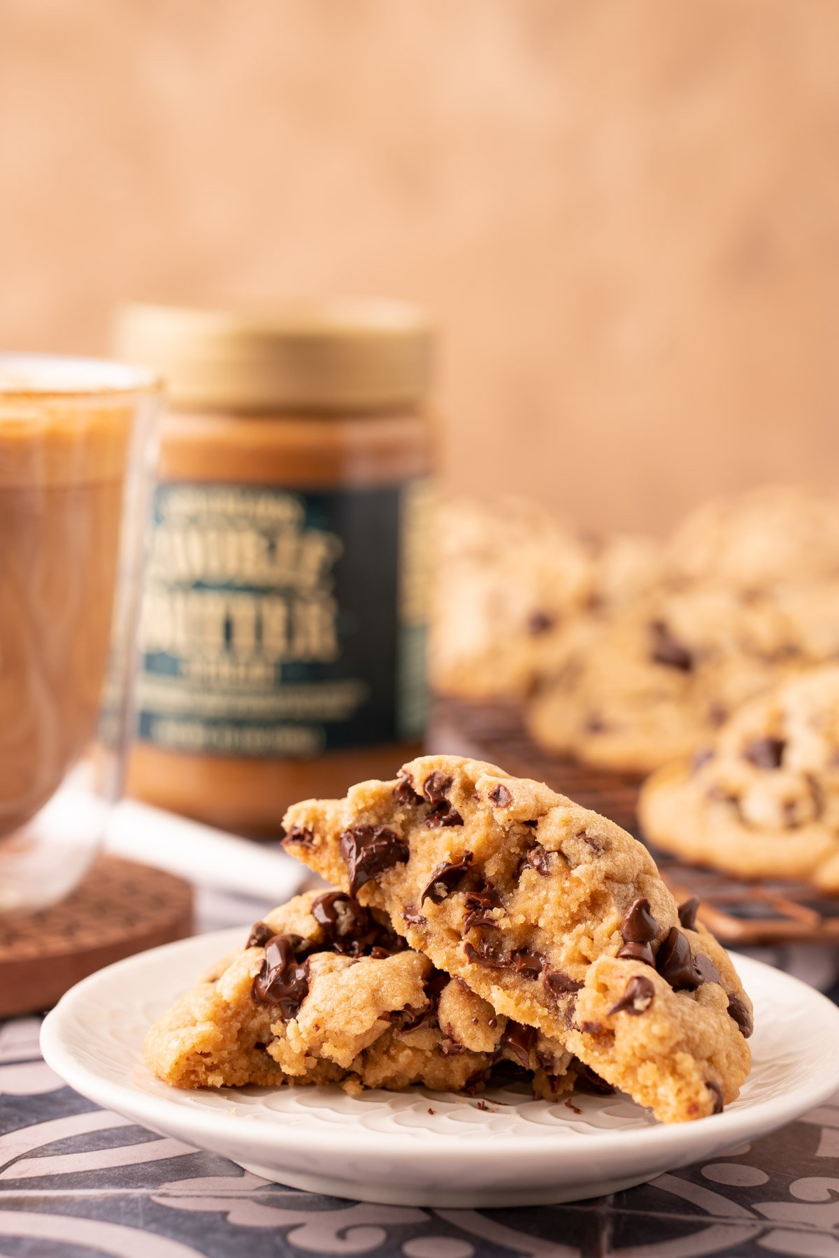 A cookie butter chocolate chip cookie broken in half on a white plate.