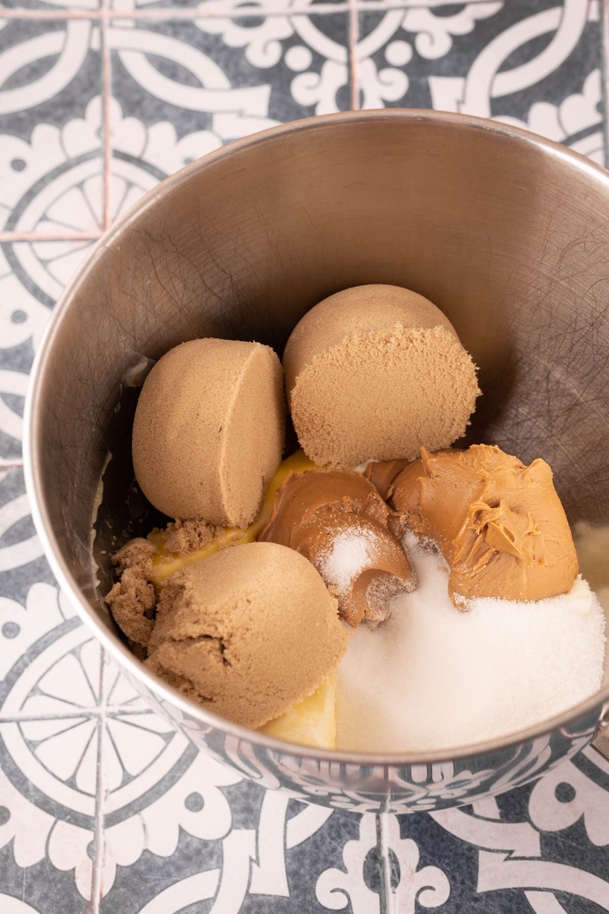 Butter, sugar, and cookie butter in a stainless steel mixing bowl ready to be mixed.